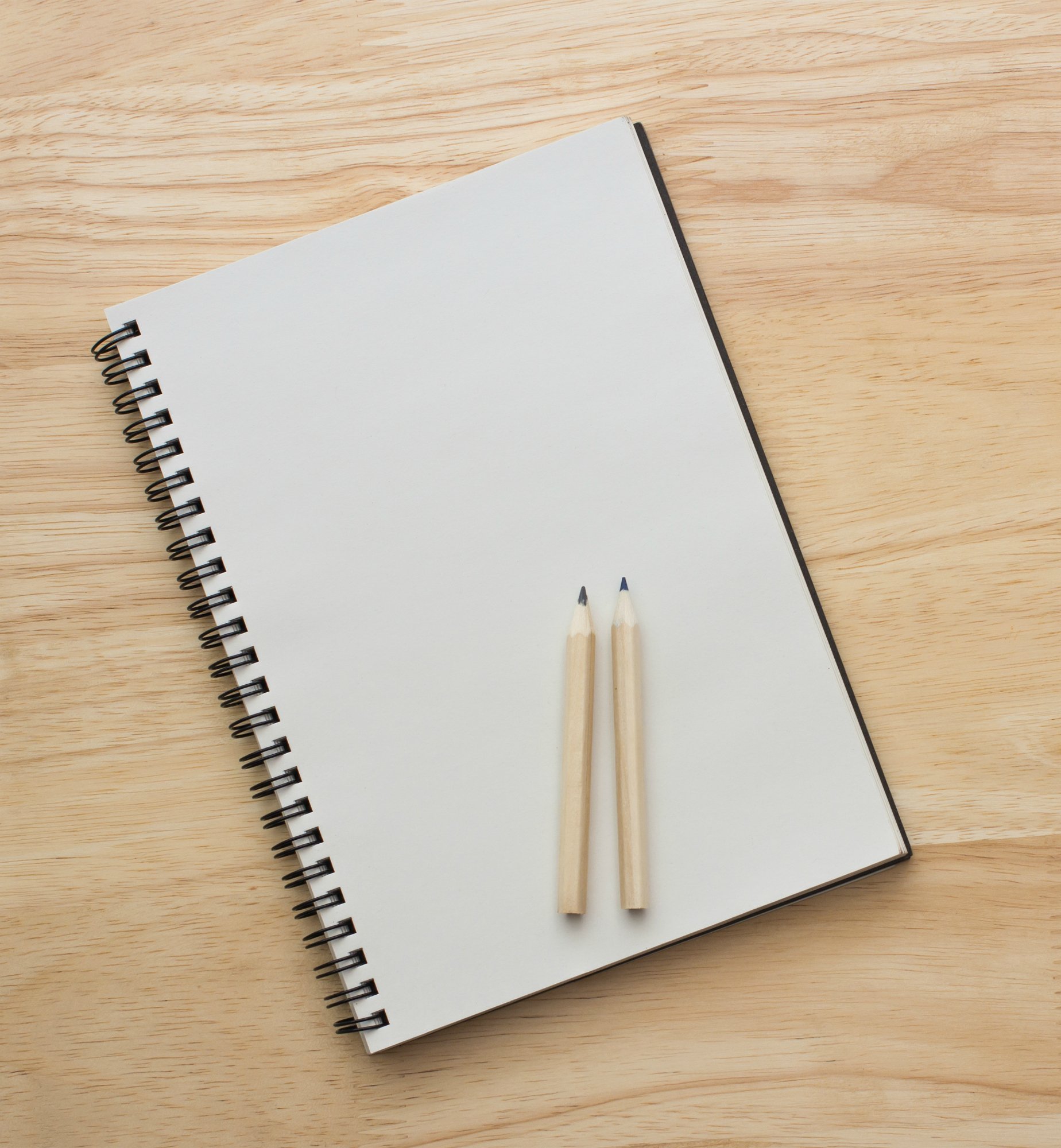 Two pencils put on  notebook and put left side wooden table desk background