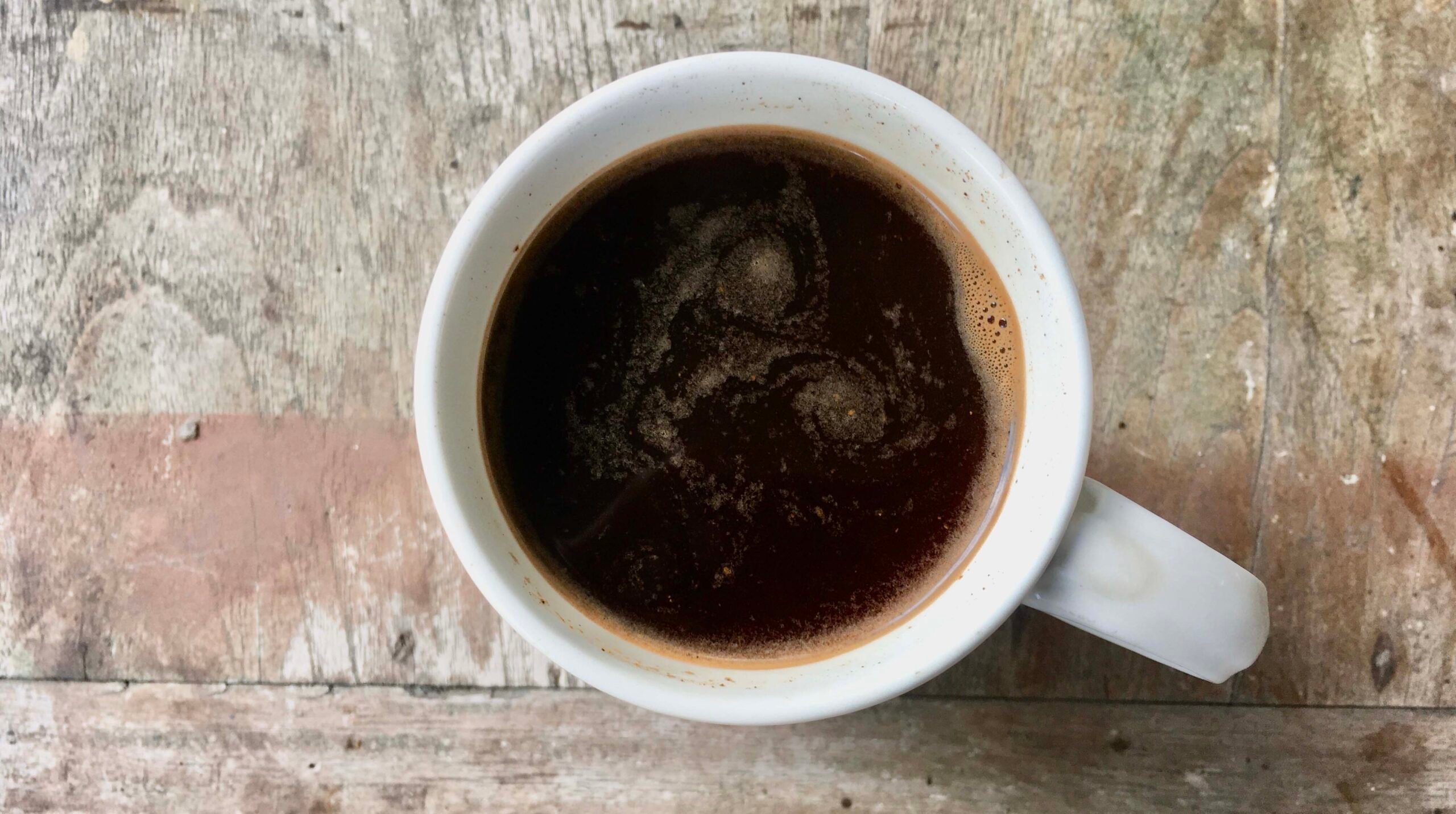 Black coffee in a white cup on a top of a old rustic table