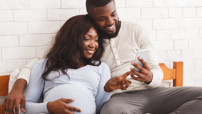pregnant woman and partner looking at smartphone