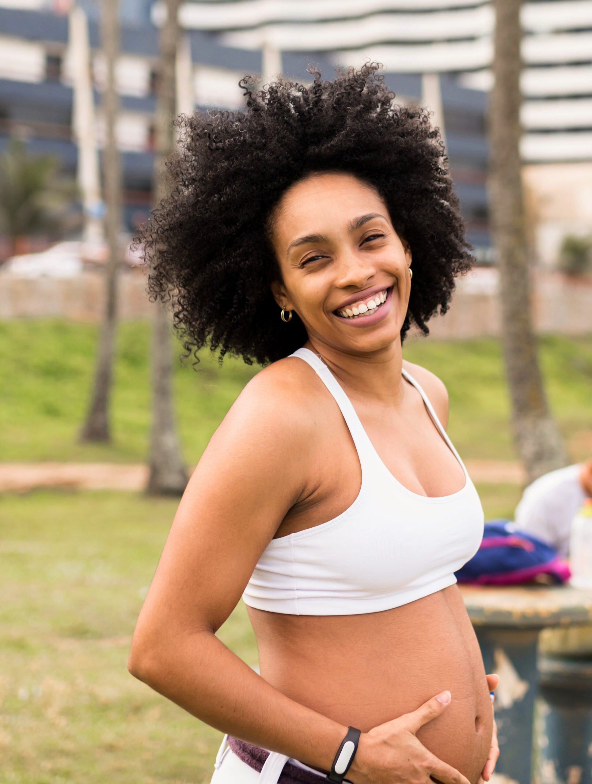 smiling pregnant afro-brazilan woman holding belly
