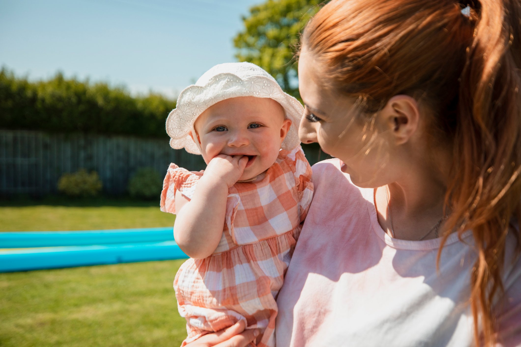 Mother holding her baby girl while enjoying summer outdoors in a garden in the North East of England.