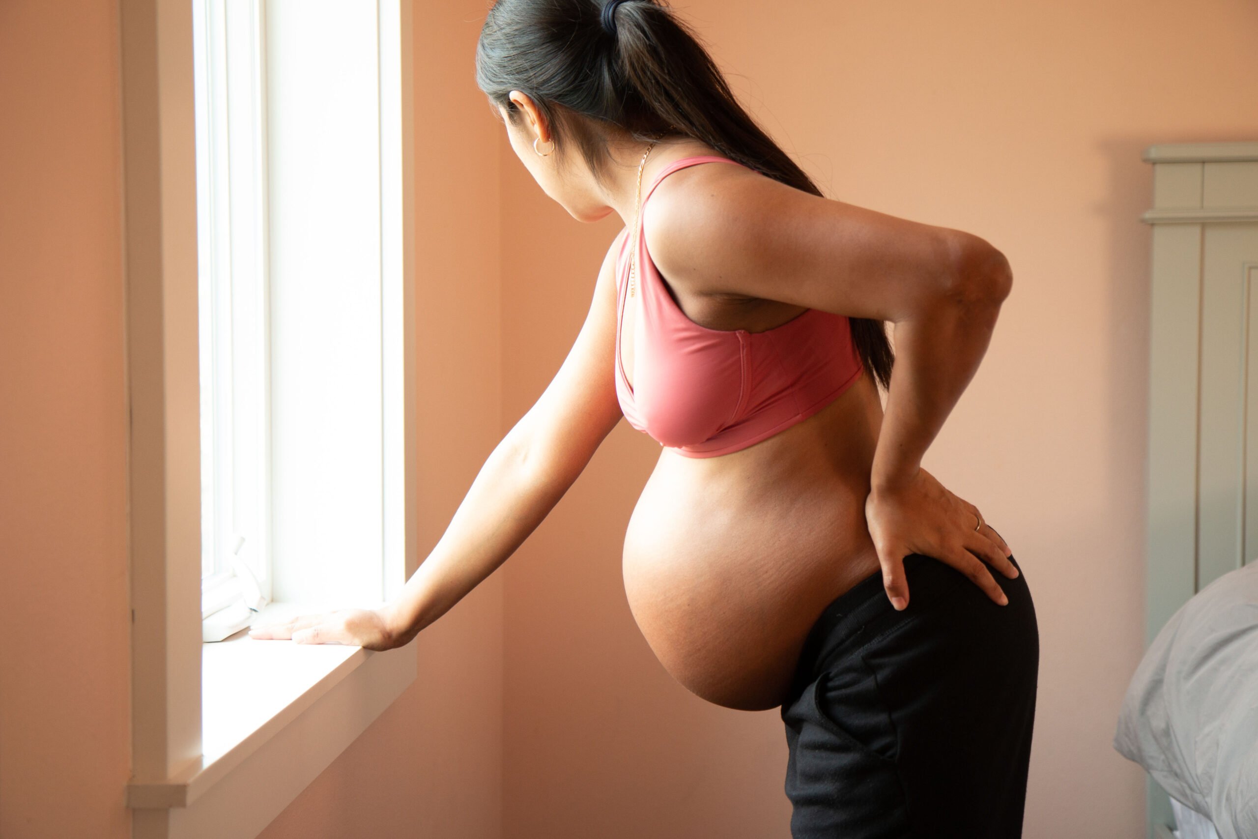 signs labor is close, Young pregnant hispanic woman coping with labor back pain.