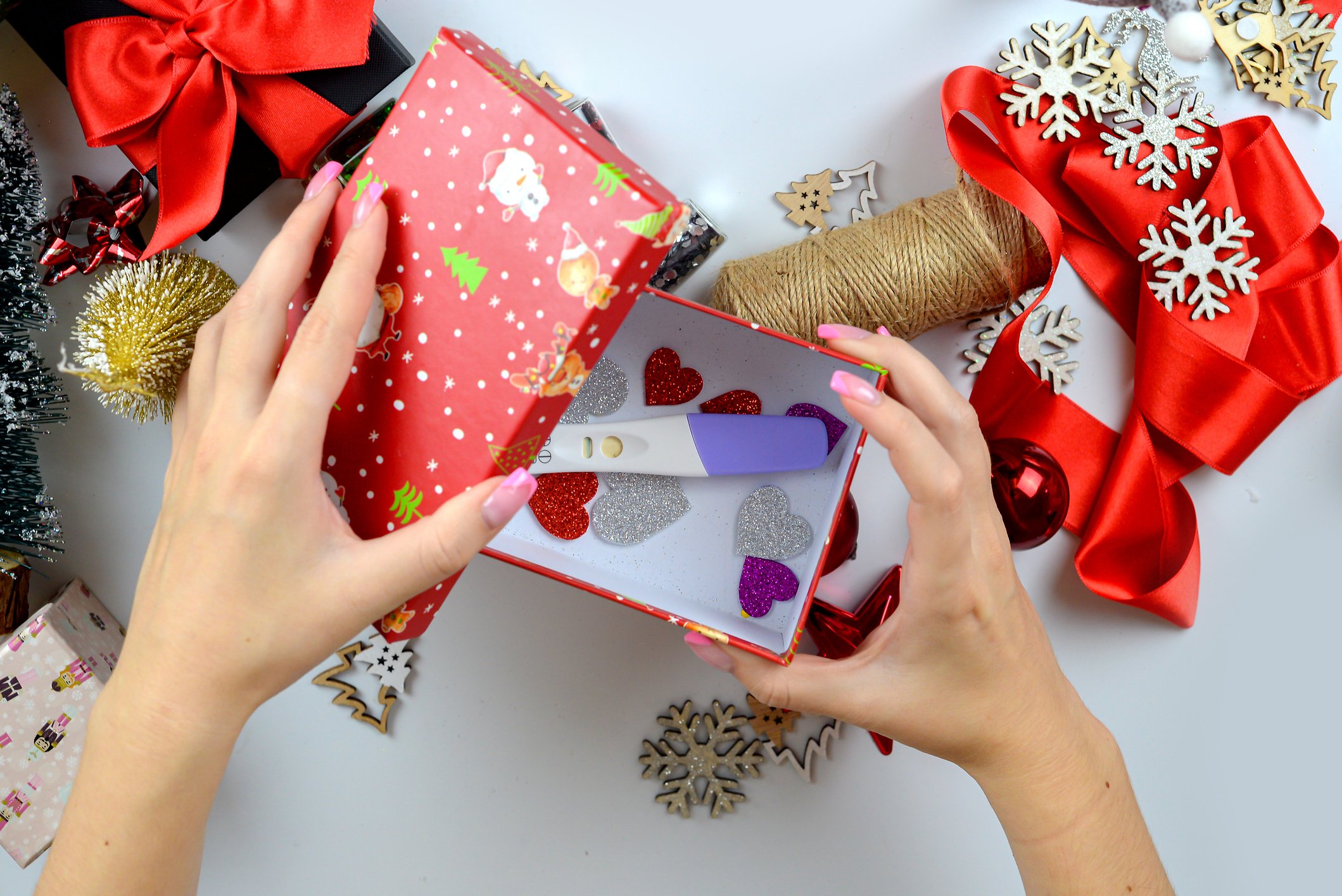 Woman's hands making a pregnancy test as a Christmas gift. table with New Year's decorations. View from above. Holiday mood, motherhood, waiting concept