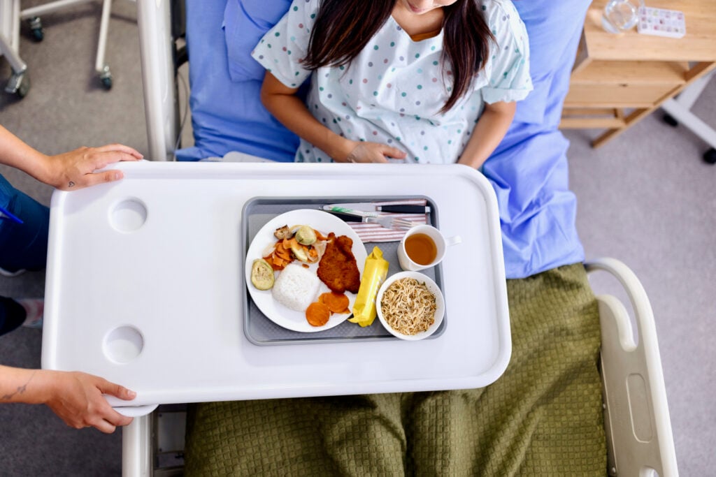 Close-up of an unrecognizable woman having lunch in the hospital room