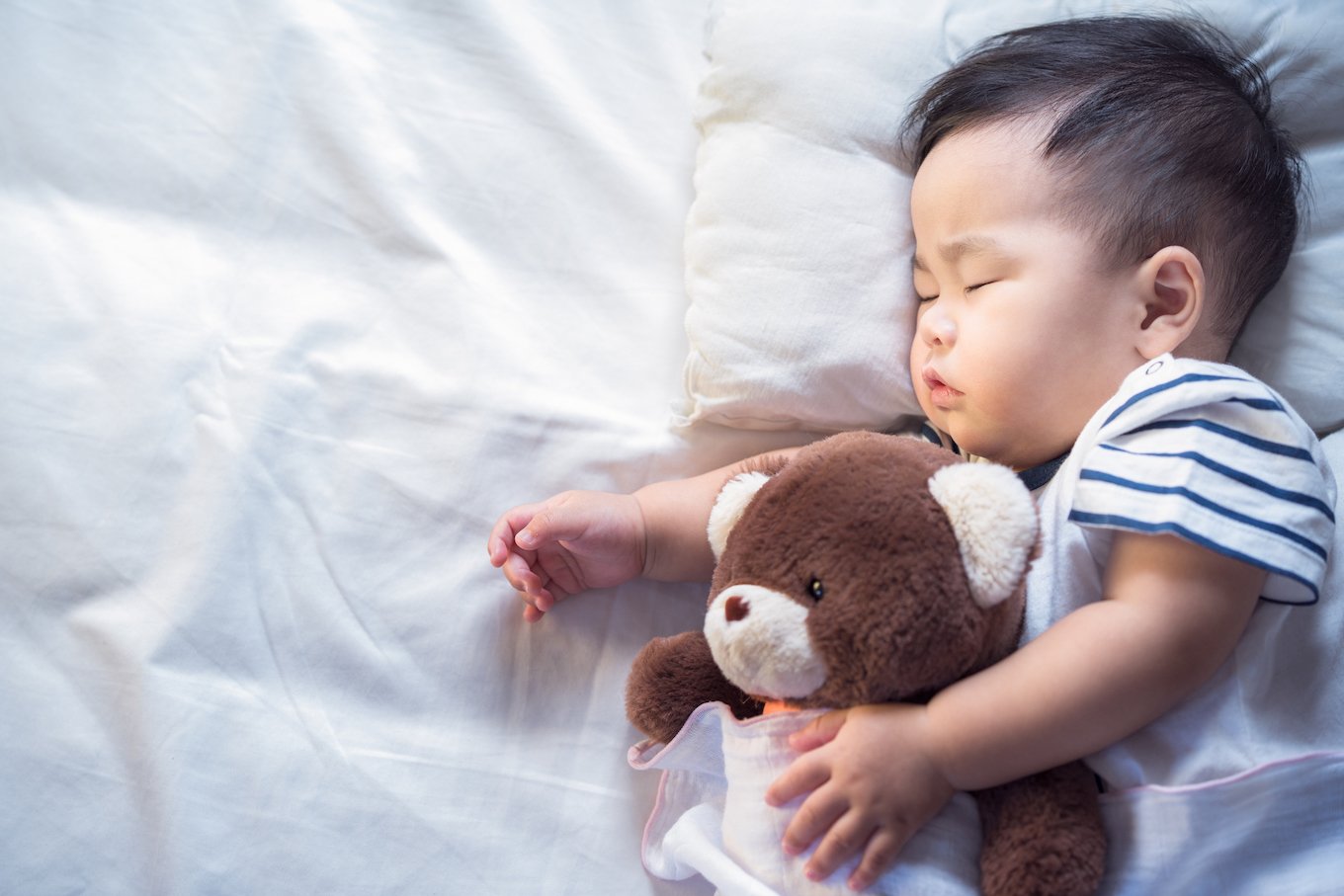 baby sleeping with a teddy bear